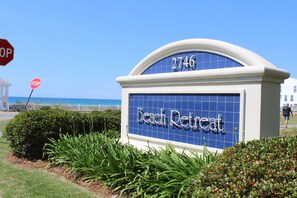 A sign for 'Beach Retreat' with the number 2746, surrounded by greenery.