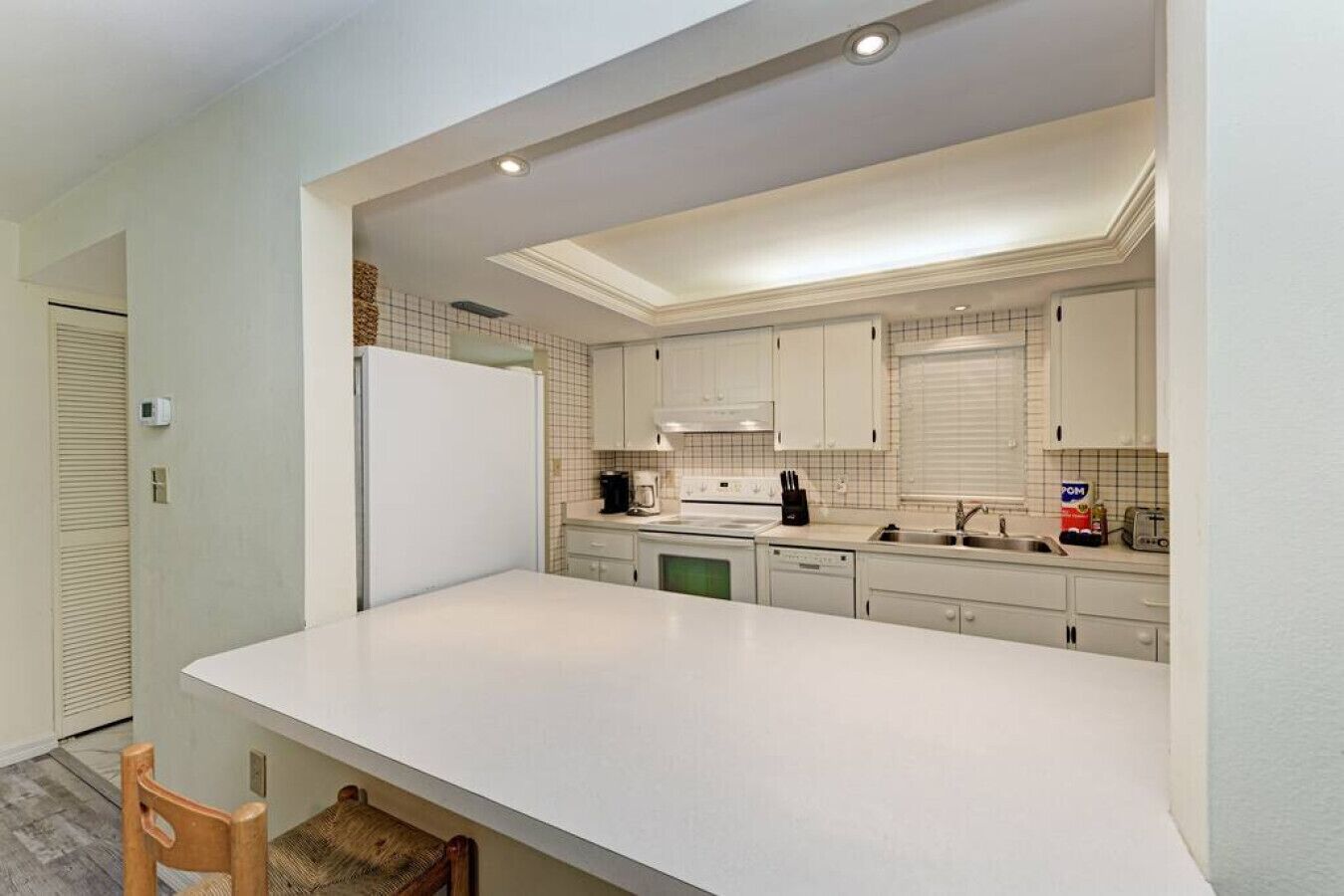 Una cocina moderna con gabinetes blancos, una isla grande y electrodomésticos integrados.