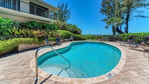 A swimming pool with lounge chairs and a building in the background. - Sea Grape Inn #3 - Beachfront Property (Longboat Key)