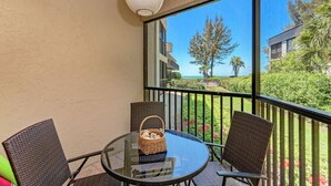 A balcony with wicker chairs, a glass table, and a wicker basket. - Sea Grape Inn #3 - Beachfront Property (Longboat Key)