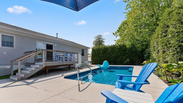 A swimming pool with blue chairs and a small deck with stairs leading to a house. - Heated Pool + Hot Tub | Fenced Yard | Walk to Delaware Bay | Tides Away (Villas)