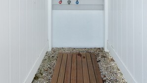 A narrow, enclosed space with a wooden deck and a shower area with pipes and a showerhead. - Heated Pool + Hot Tub | Fenced Yard | Walk to Delaware Bay | Tides Away (Villas)