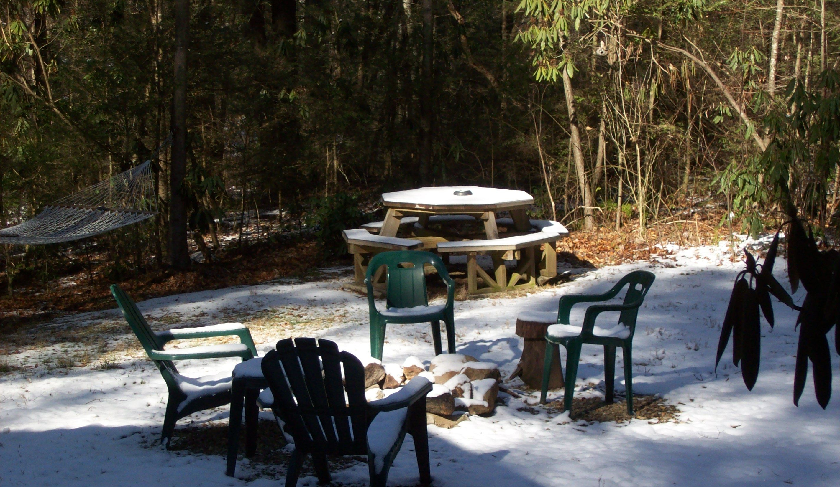 A snow-covered outdoor seating area with a picnic table and chairs.