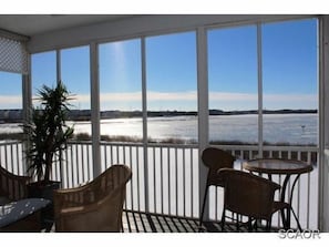 Relax in this serene outdoor space with a view of a frozen landscape, featuring a wicker chair and small table for dining or unwinding.