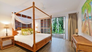 Ein Bett mit Baldachin, ein Nachttisch mit Lampe und Blick ins Freie durch eine Glastür.