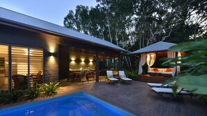 Ein modernes Haus mit Swimmingpool, Sitzgelegenheiten im Freien und einer gut beleuchteten Terrasse.