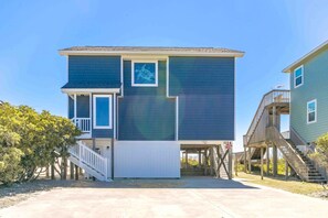 A two-story residential building with a covered front porch and a staircase leading to a deck.
