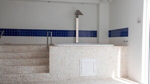 Casa de banho com degraus de pedra, lavatório branco e paredes revestidas de azulejos azuis.