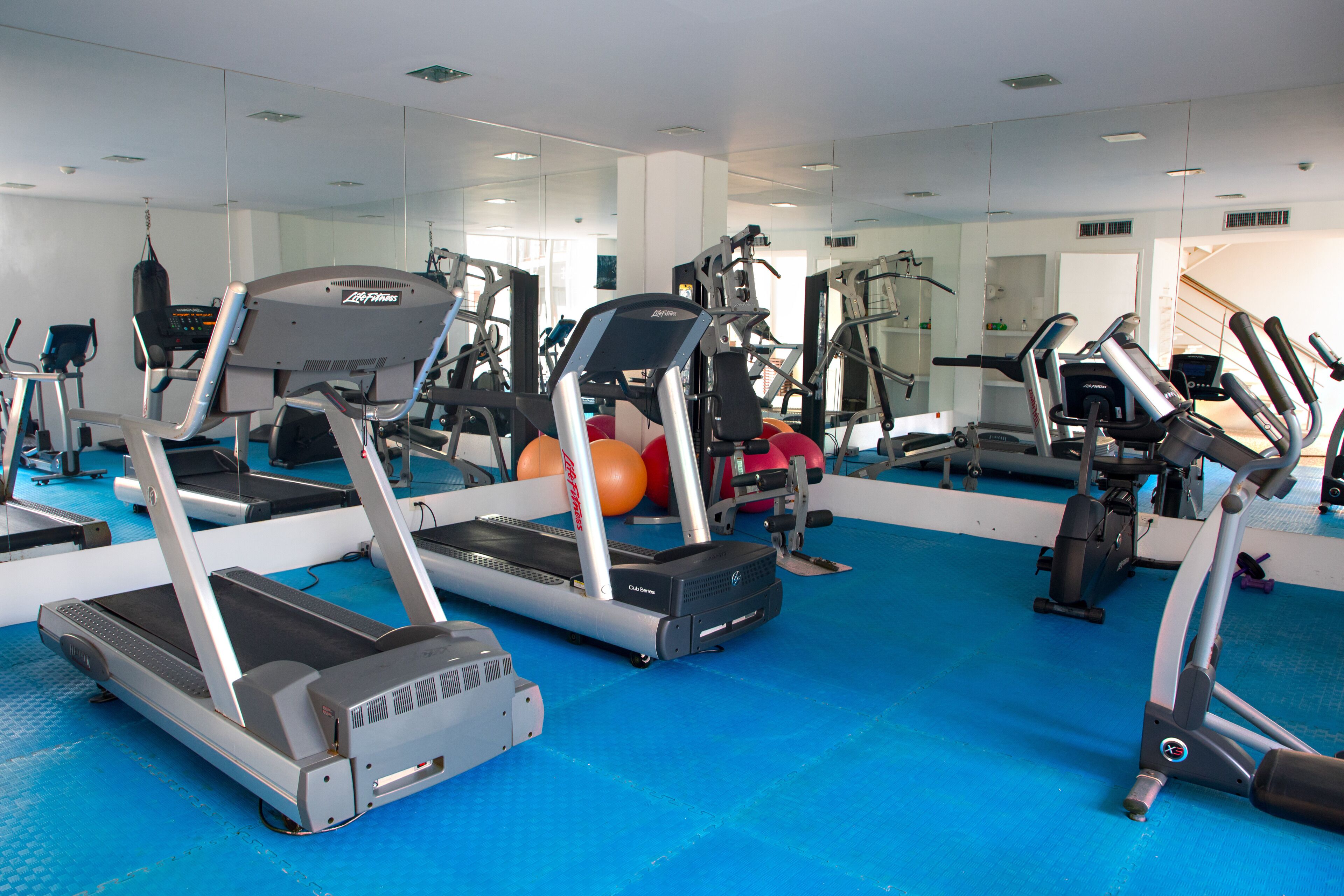 A gym with treadmills, elliptical machines, and exercise balls.