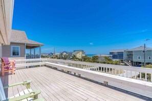 A wooden deck with a railing, overlooking a residential area and a body of water. - Flip Flops - Cozy 2nd Row Home - Ocean Views! (Surf City)