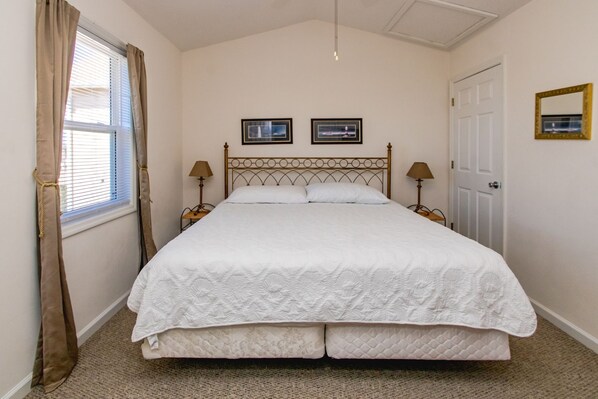 A single bed with a headboard, two bedside lamps, a door, and two framed pictures on the wall. - Flip Flops - Cozy 2nd Row Home - Ocean Views! (Surf City)