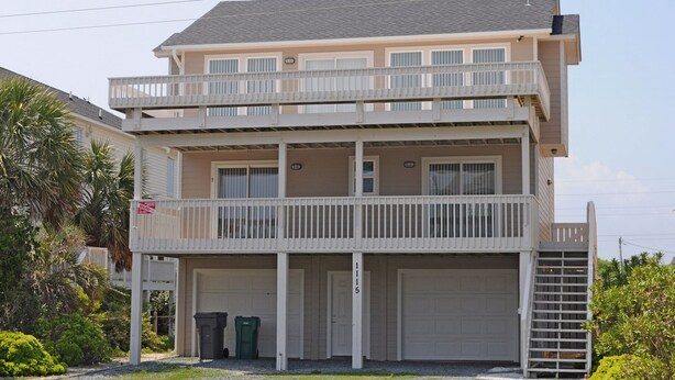 A two-story residential building with a balcony, a garage, and a small staircase leading to the upper level. - Flip Flops - Cozy 2nd Row Home - Ocean Views! (Surf City)