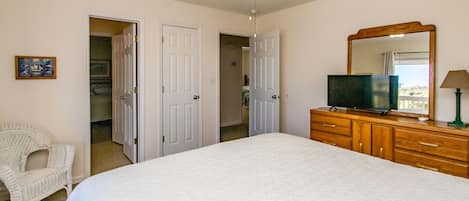 Un dormitorio con cama, cómoda, televisor, silla y ventilador de techo.
