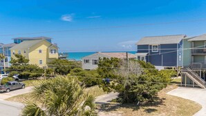 A coastal residential area with houses, a clear blue sky, and a view of the ocean. - Flip Flops - Cozy 2nd Row Home - Ocean Views! (Surf City)