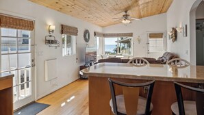 A spacious kitchen with a large island, wooden ceiling, and a view of the ocean through large windows. - MAGICAL 5-STAR RATED OCEAN VIEW CUSTOM HOME - PLEASE READ ALL 400 GUEST REVIEWS! (Summerland)