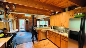 Una cucina con mobili in legno, un frigorifero in acciaio inossidabile e uno schienale rivestito di piastrelle.