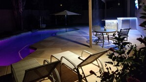An outdoor patio with a pool, seating, and a bar area.