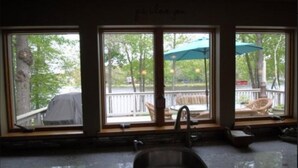 Une cuisine dotée de grandes fenêtres, d’un évier et offrant une vue sur une terrasse aménagée avec du mobilier d’extérieur.