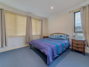 Ein Schlafzimmer mit einem Bett, einem Nachttisch und einem Fenster mit Vorhängen.