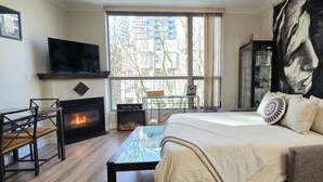 Een slaapkamer met een bed, een televisie, een open haard, een groot raam en een schilderij.
