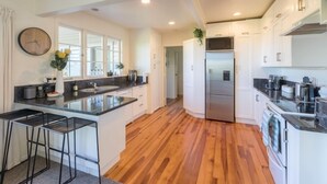 Una cocina moderna con armarios blancos, un refrigerador de acero inoxidable y piso de madera.