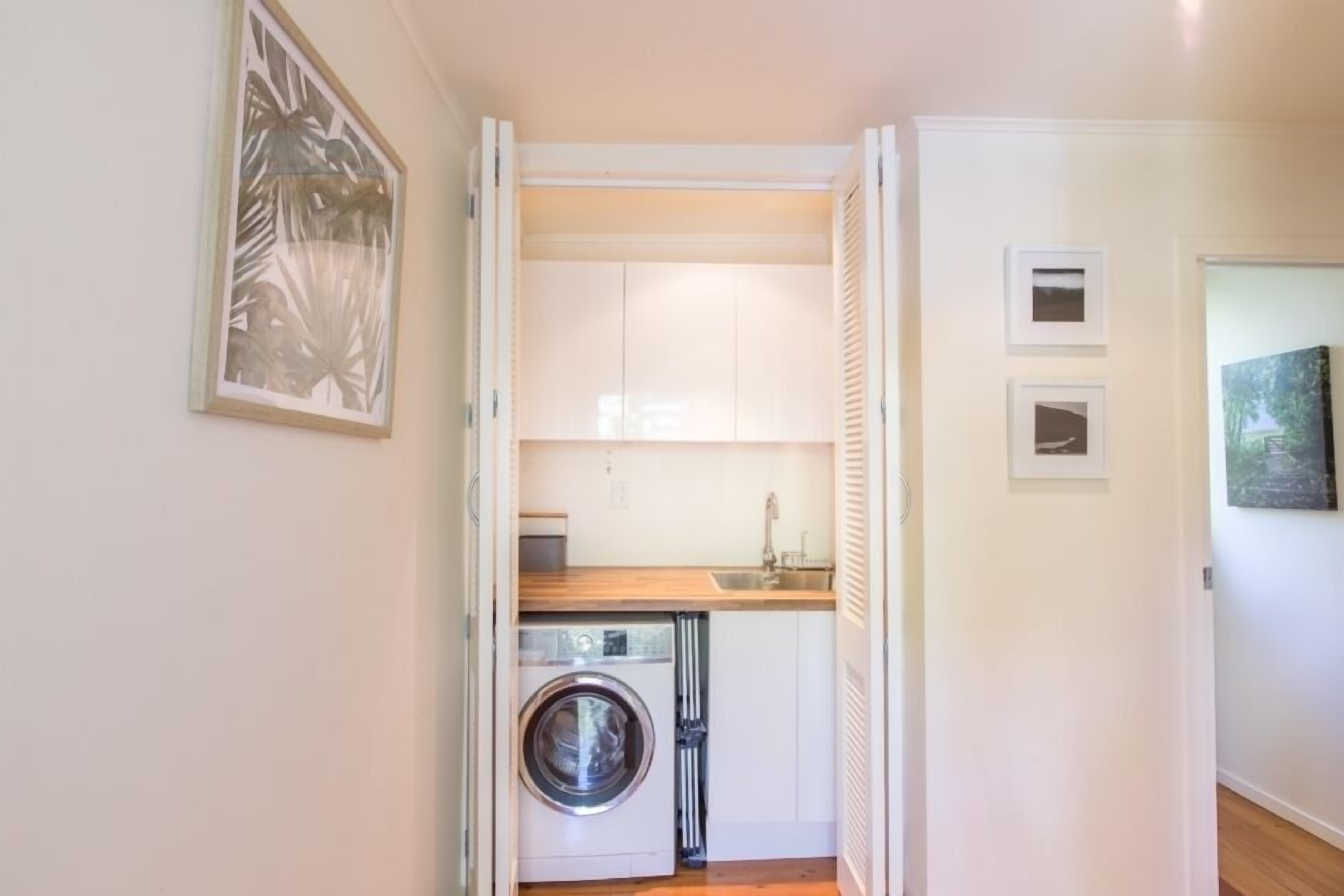 A compact laundry room with a washing machine, a sink, and a countertop.