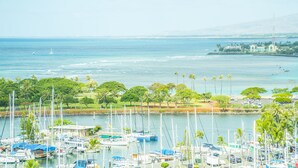 Un port de plaisance où sont amarrés de nombreux bateaux, entouré de palmiers et offrant une vue sur l’océan.