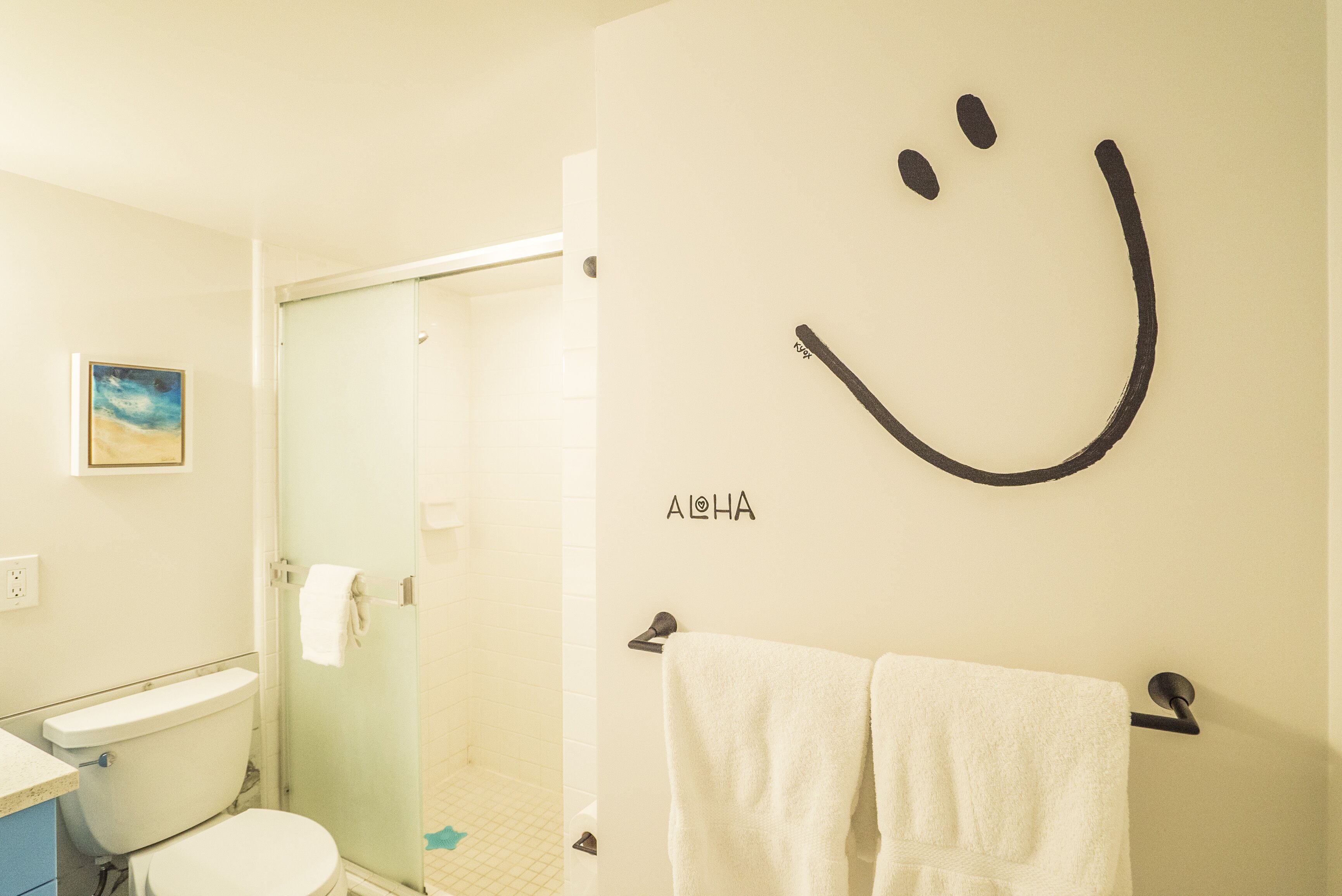 Un baño con inodoro, ducha y un perchero con dos toallas.