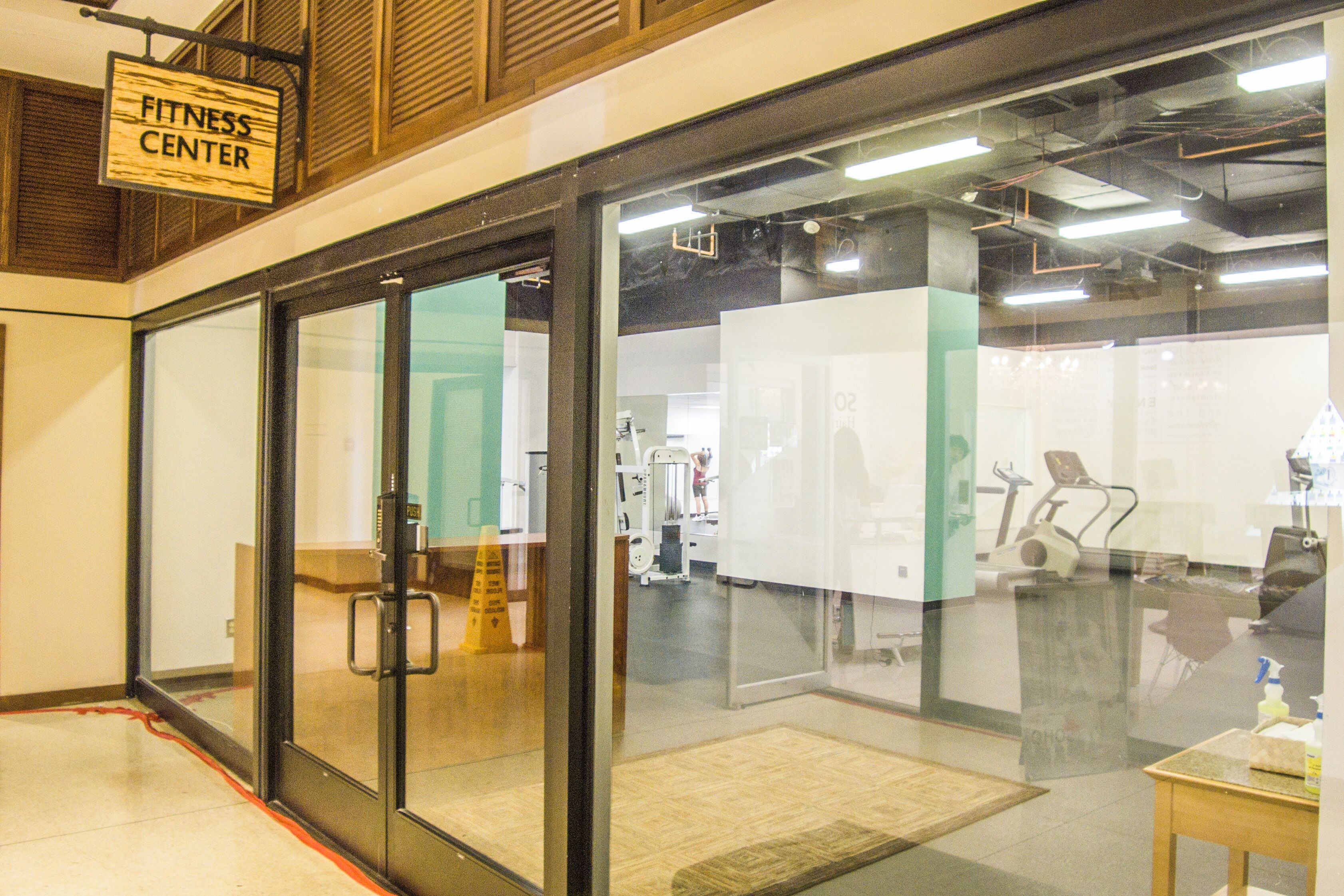 Une salle de sport avec des portes en verre, du matériel d’exercice et un panneau indiquant l’emplacement.