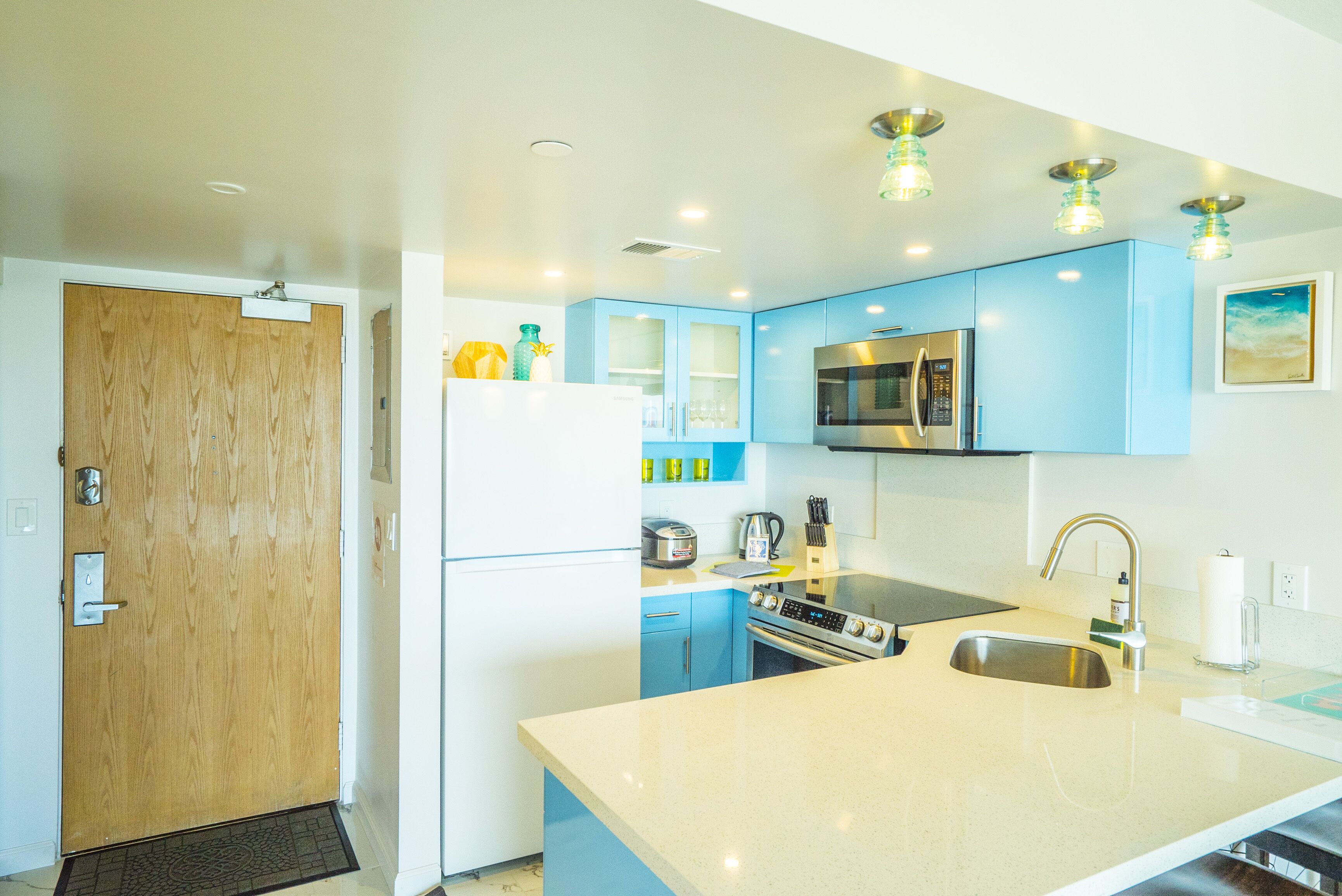 Een moderne keuken met blauwe kastjes, roestvrijstalen apparatuur en een groot eiland met een spoelbak.