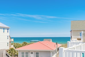 A coastal residential area with houses, a red-roofed building, and a view of the ocean. - Hoos at the Beach - Lovely 4 BR Sea Star Village Townhouse; Ocean View! (Surf City)