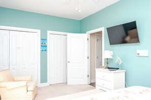 Une chambre à coucher avec un lit, une commode, un téléviseur et une porte.