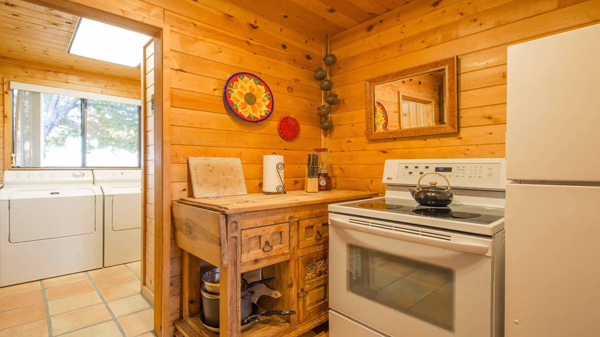 A wooden cabin kitchen with a stove, oven, and a large window.