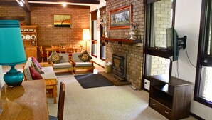 Una sala de estar acogedora con chimenea, muebles de madera y una televisión.