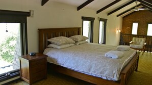 Un dormitorio con cama de madera, una mesita de noche, una silla y vistas al exterior.