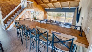 Een moderne keuken met een houten bar en barkrukken, een trap en uitzicht op het terras.