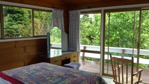 A bedroom with a bed, a dresser, a television, and a view of greenery through large windows. - Private and pet friendly lockwood house (Okiato)