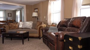 A living room with a brown leather sofa, a beige sofa, a coffee table, and a dark wooden cabinet. - Geauga Maple Cottage (Chardon)