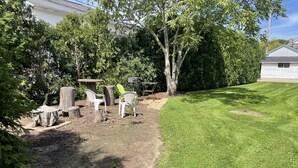 A backyard with a lawn, a tree, and outdoor furniture. - Geauga Maple Cottage (Chardon)