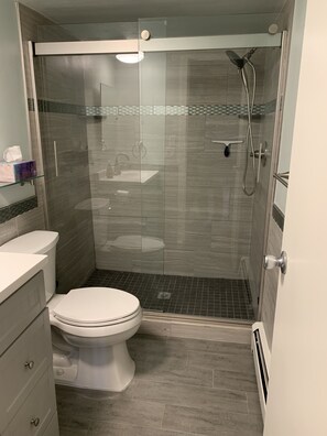 Een bad/douchecombinatie, een haardroger, handdoeken, zeep