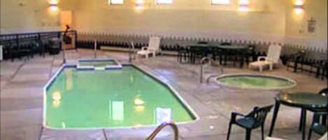 Zona de piscina con trampolín, sillas de descanso y un jacuzzi pequeño.