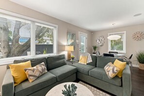 A modern living room with a sectional sofa, a round coffee table, and a dining area with a table and chairs.