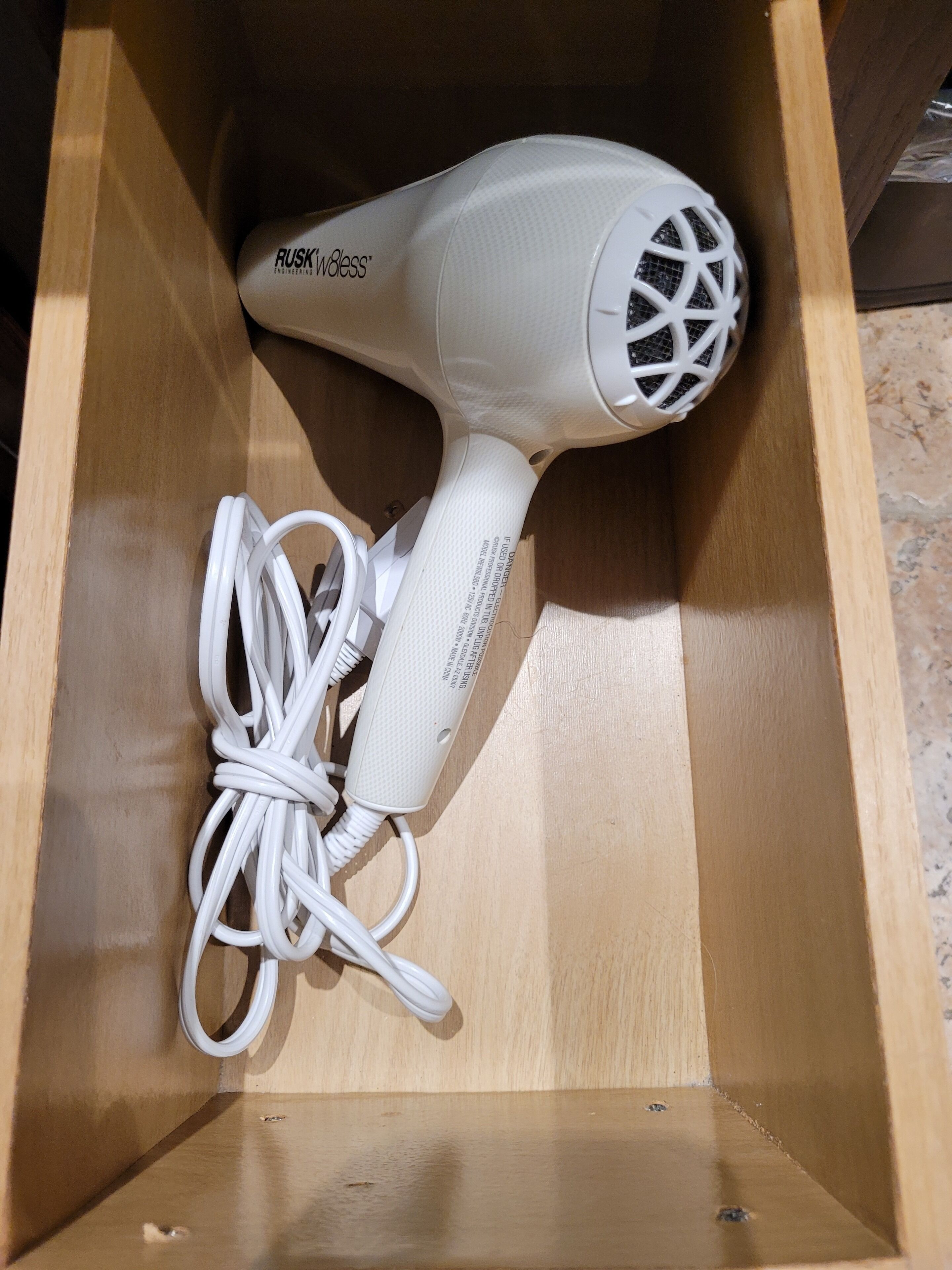 A white hair dryer with a cord inside a wooden box.