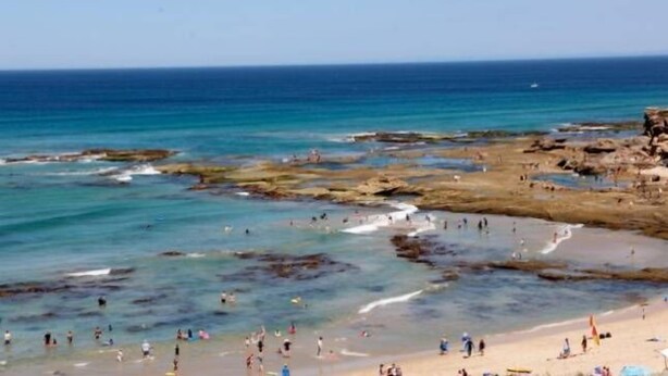 Uma praia costeira com formações rochosas e águas azul-claras.