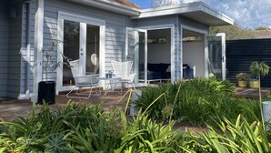 Uma casa com varanda coberta, móveis de jardim brancos e diversas plantas.