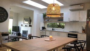 Cozinha moderna com área de refeições, com luminária pendente, relógio e vista para o exterior.