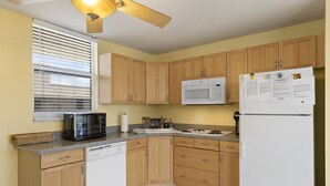 Eine Küche mit Holzausstattung, einer Mikrowelle, einem Kühlschrank, einem Geschirrspüler und einem Deckenventilator.
