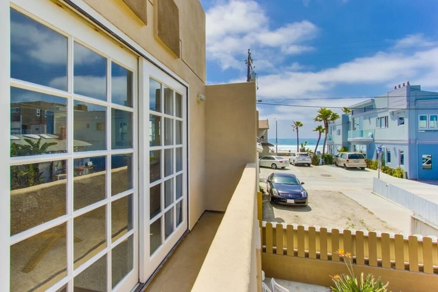 A residential building with large windows, a balcony, and a view of the street and ocean.