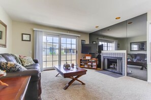 A living room with a fireplace, a television, and a sofa. - Oceanview from rooftop patio, parking, bikes, pets (San Diego)