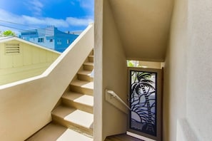 Una escalera con peldaños color beige que lleva a una puerta con un diseño de palmera.
